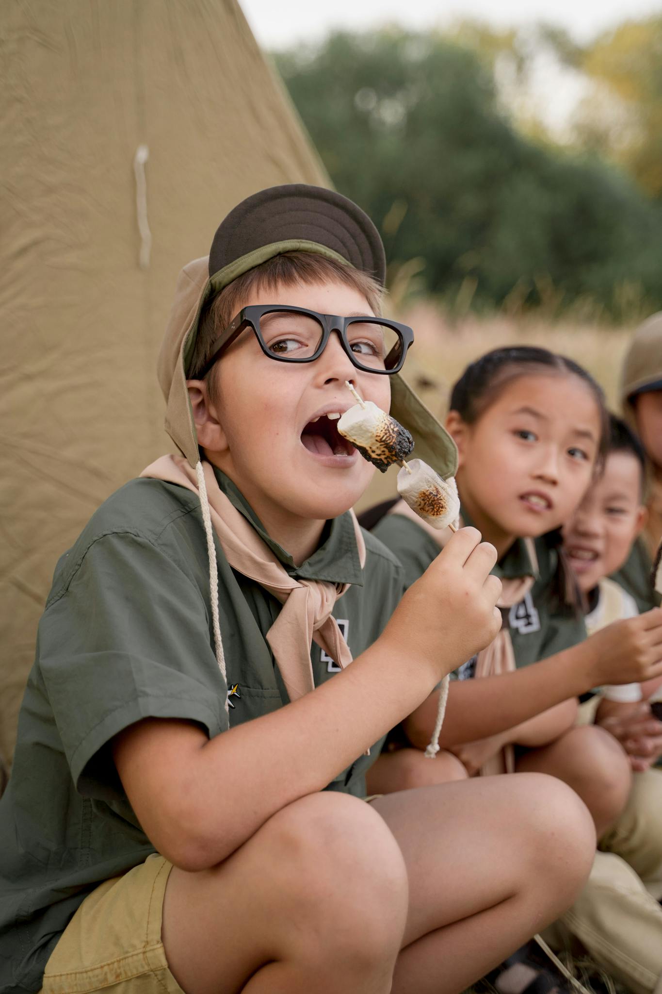 Kids at a campsite roasting and enjoying marshmallows together.