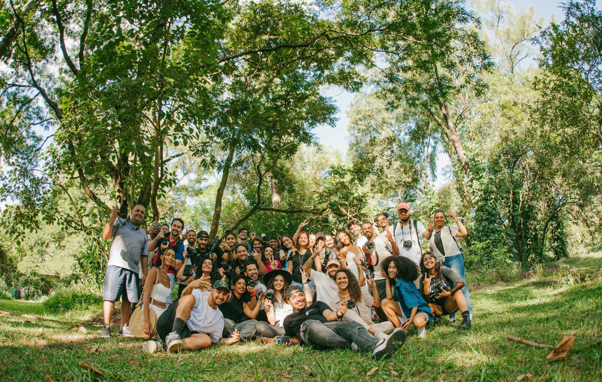 Large group of diverse friends enjoying a sunny day in a vibrant green park.